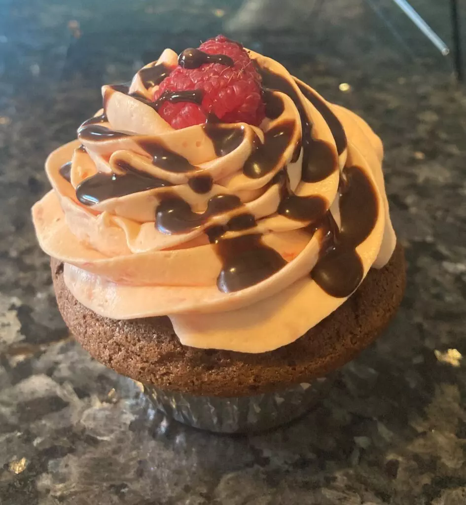chocolate cupcake with raspberry whipped cream frosting and chocolate drizzle