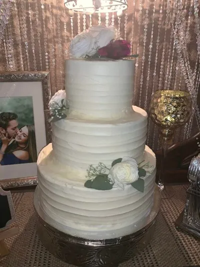 simple three-tiered wedding cake, lightly textured, with silk flowers