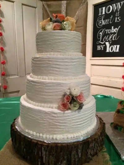 four-tiered wedding cake with textured buttercream and soft pastel flowers