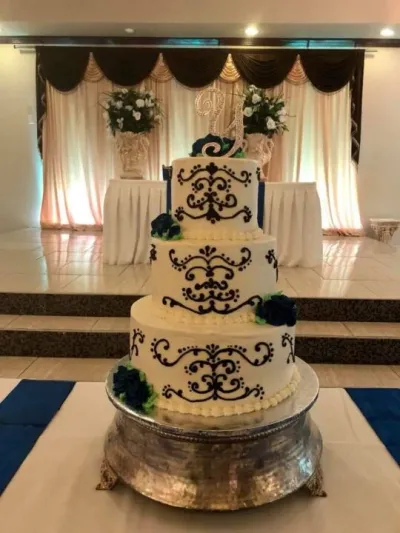 tall three-tiered white wedding cake on stand with pretty black piping