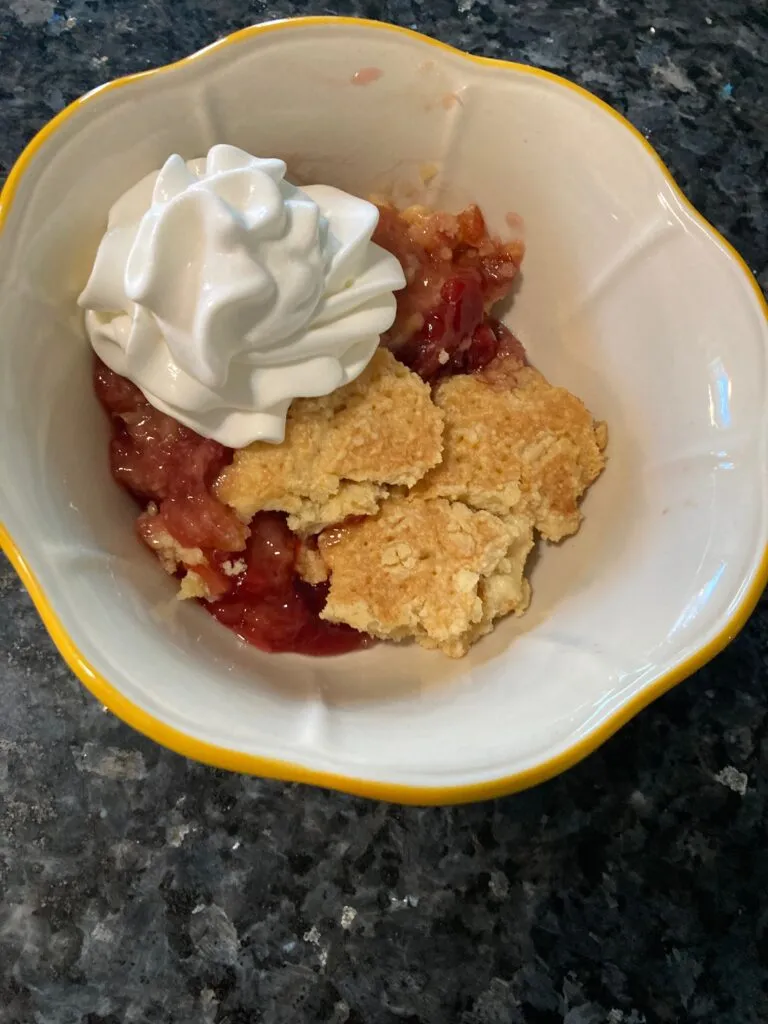 bowl of pineapple upside down dump cake with whipped topping